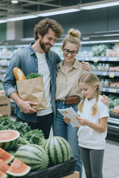 Семейный поход за продуктами, пока ребенок читает этикетку на продукте. - SeventyFour