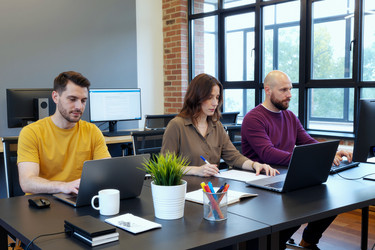 Команда сотрудников работает на ноутбуках в современном офисном режиме для совместной работы. - SeventyFour