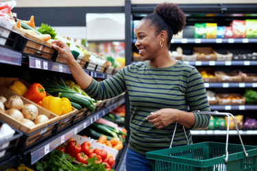 Темнокожая женщина выбирает свежие продукты для здоровых покупок в продуктовом магазине. - SeventyFour