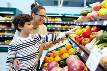 Мать и ребенок выбирают свежие продукты для здоровых покупок в продуктовом магазине. - SeventyFour