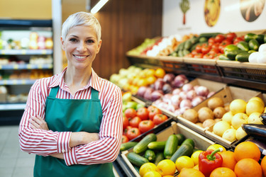 Портрет женщины средних лет, стоящей в отделе овощей и фруктов в продуктовом магазине. - SeventyFour
