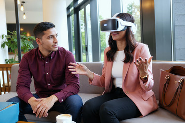 Взрослая женщина в vr-гарнитуре во время демонстрации продукта с мужчиной - DragonImagesAsia