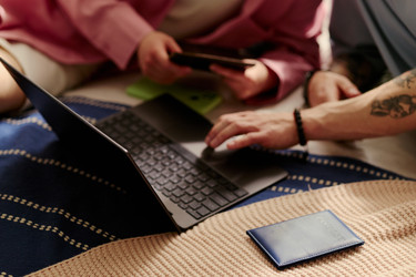 Взрослая пара, использующая ноутбук и смартфон для онлайн-планирования путешествий - DragonImagesAsia