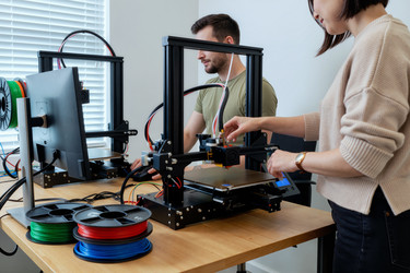 Взрослые мужчина и женщина, работающие с 3d-принтерами для создания прототипов изделий - AnnaStills
