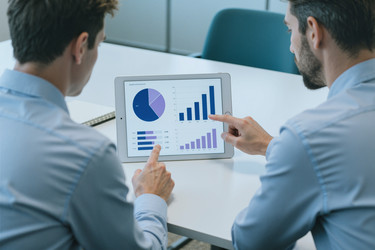 Взрослые бизнесмены просматривают аналитику продаж на планшете во время совещания - Pressmaster