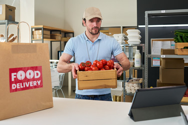 Мужчина готовит заказ продуктов для службы доставки еды - Pressmaster