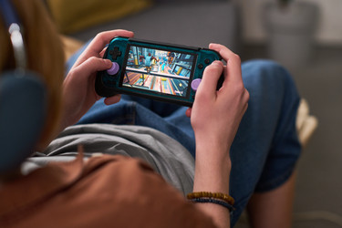 Мальчик-подросток играет дома в портативную игровую приставку - Pressmaster