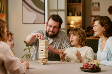 Родители и дети играют в игру "укладка" после семейного обеда дома - AnnaStills
