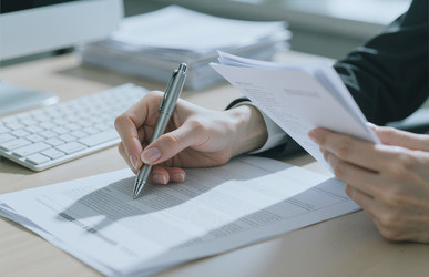 Деловая женщина рассматривает документы и подписывает контракт в офисе - Pressmaster