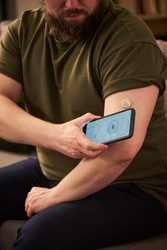 Взрослый мужчина, контролирующий диабет с помощью смартфона дома - Mediaphotos
