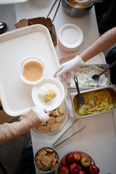 Взрослый волонтер, раздающий еду в продуктовой линии центра гуманитарной помощи - SeventyFour