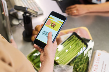 Взрослая женщина расплачивается смартфоном во время покупки продуктов - Pressmaster