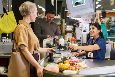 Женщина средних лет с диабетом платит за продукты в супермаркете - Pressmaster
