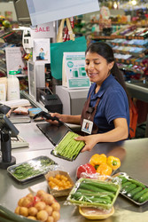 Кассирша-латиноамериканка просматривает продукты на кассе супермаркета - Pressmaster