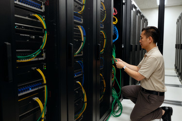 Азиат управляет серверными кабелями в инфраструктуре центра обработки данных - DragonImagesAsia