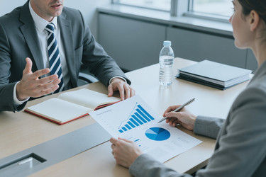 Бизнесмен обсуждает финансовый отчет с женщиной на встрече - Pressmaster