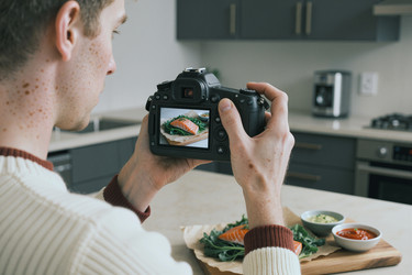 Взрослый мужчина фотографирует блюдо из лосося для маркетинга кулинарного блога - Mediaphotos