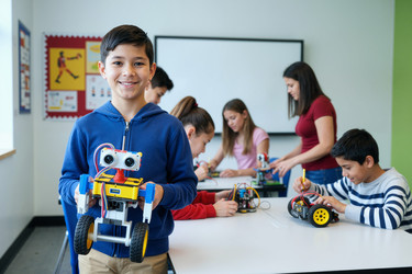 Портрет школьника, держащего робота в руках в мастерской stem classroom - AnnaStills