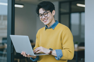 Азиат использует ноутбук для удаленной работы в современном офисе - Pressmaster