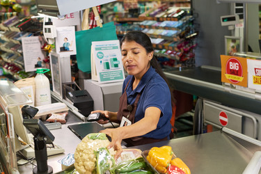 Испаноязычная женщина-кассир, обслуживающая покупателей на кассе продуктового магазина - Pressmaster