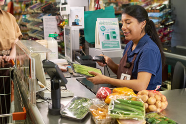 Кассирша-латиноамериканка просматривает продукты - Pressmaster