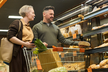 Пара средних лет покупает продукты в пекарне супермаркета - Pressmaster