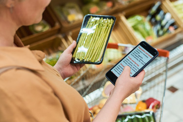 Взрослая женщина сравнивает список продуктов на смартфоне в супермаркете - Pressmaster