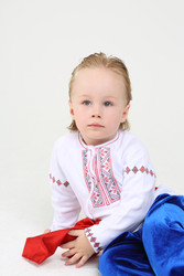 Маленький симпатичный мальчик в русском национальном костюме сидит на полу на белом фоне - paha_l