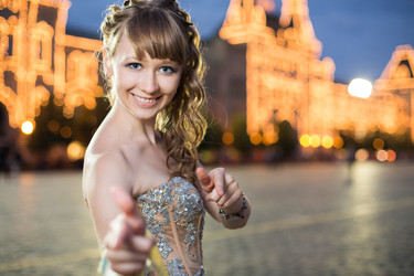 Улыбающаяся девушка в красивом платье стоит на красной площади рядом с освещенным ГУМом - paha_l