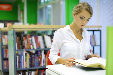 Молодая женщина читает книгу в читальном зале библиотеки - paha_l