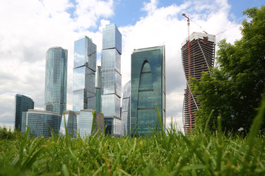 МОСКВА - 13 ИЮНЯ: Городской пейзаж с небоскребами делового комплекса «Москва-Сити» на фоне зеленой травы и голубого неба с облаками. Фотография сделана 13 июня 2013 года в Москве, Россия - paha_l