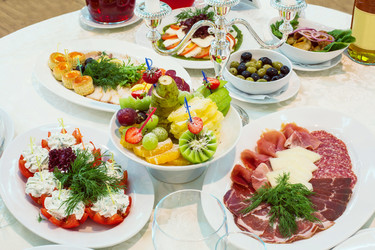 На столе разнообразные закуски из мяса, фруктов и овощей - paha_l