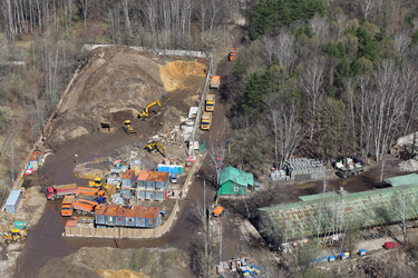 Вид сверху на небольшую строительную площадку в лесу, где много грузовиков и техники - paha_l