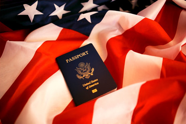 Паспорт США лежит на сложенном американском флаге, на котором крупным планом отчетливо видны красные, белые и синие цвета - Darya Petrenko