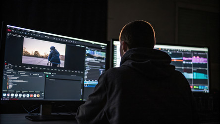 Видеомонтажер работает над контентом в темной студии. Генеративный ИИ - RomanZ