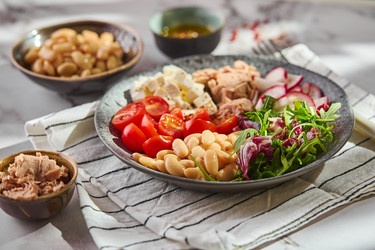 Полезный салат из тунца с белой фасолью, сыром фета, помидорами, редисом и зеленью на мраморном столе - Irrin0215
