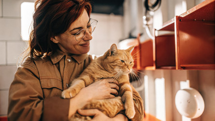 Сотрудница приюта улыбается, держа на руках кошку и весы Purrirz Scale. Генеративный ИИ - RomanZ