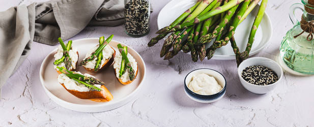 Вкусные бутерброды с рикоттой и свежей спаржей на тарелке на столе (веб-баннер) - Elena Rui