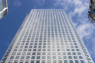 Вид снизу на небоскреб One Canada Square на фоне голубого неба с легкими облаками в районе Кэнэри-Уорф, Лондон - Tartezy
