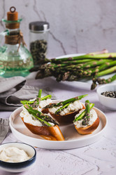 Вкусные бутерброды с рикоттой и свежей спаржей на тарелке на столе (вертикальный вид) - Elena Rui