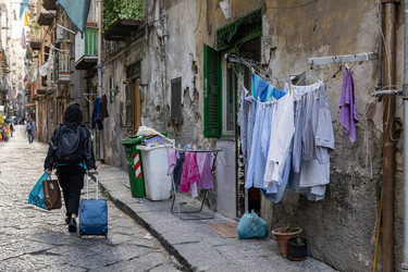 Италия. Неаполь. Женщина идет с чемоданом на узкой улочке.   Italy. Naples. Woman Walking Down a Narrow Alley Carrying Suitcase - ffoto-graff