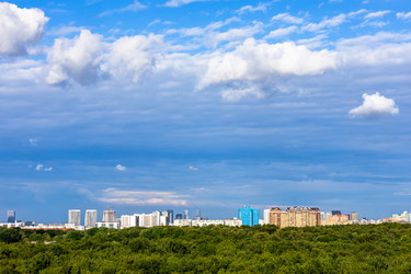 Темно-синее небо с облаками над городом и зеленым парком - vale