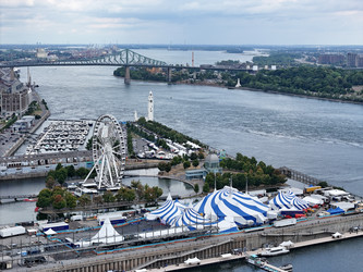 24 июня 2026 года. Полет дрона над бело-голубым шатром Cirque du Soleil в Старом порту Монреаля на фоне городского пейзажа - EOS_Canon