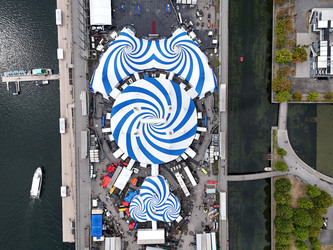 24 июня 2026 года. Полет дрона над бело-голубым шатром Cirque du Soleil в Старом порту Монреаля на фоне городского пейзажа - EOS_Canon