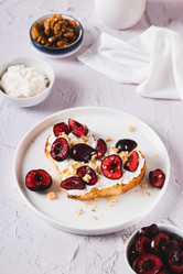 Вкусный тост со сливочным сыром и вишнями на тарелке на столе (вертикальный вид) - Elena Rui