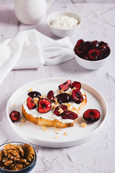 Вкусные бутерброды с рикоттой, вишней и орехами на тарелке на столе (вид сверху) - Elena Rui