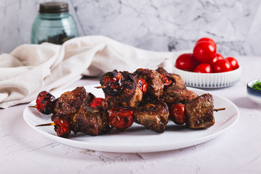 Вкусный кебаб на шампурах с помидорами, приготовленный во фритюрнице, на тарелке на столе - Elena Rui