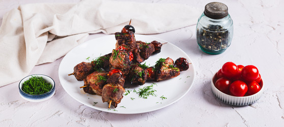 Вкусный кебаб на шампурах с помидорами, приготовленный во фритюрнице, на тарелке на столе (веб-баннер) - Elena Rui