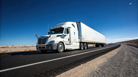 Грузовик Freightliner едет по широкой дороге под ясным небом. Генеративный искусственный интеллект - RomanZ