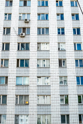Вертикальный снимок типичного городского жилого дома из сборных железобетонных панелей с множеством окон и балконов - DmitryKurullin